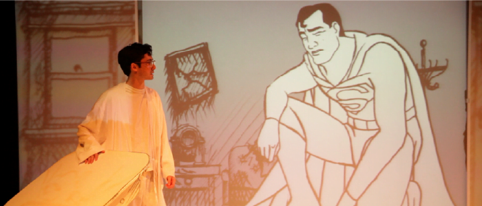 actor standing infront of a sad looking animated projection of superman
