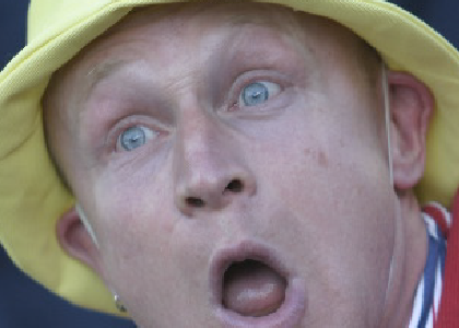 closeup of a surprised actor in a yellow hat and red vest