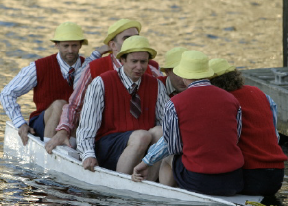 six actors with yellow hats and red vests in a wee sinking boat