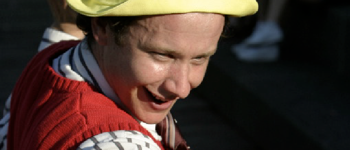 closeup of an actor with yellow hat and red vest