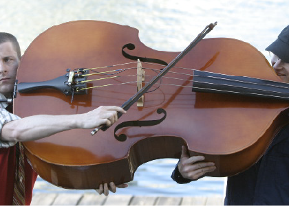 two people holding up a large string bass