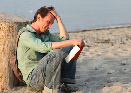 a distraught man siting on a beach