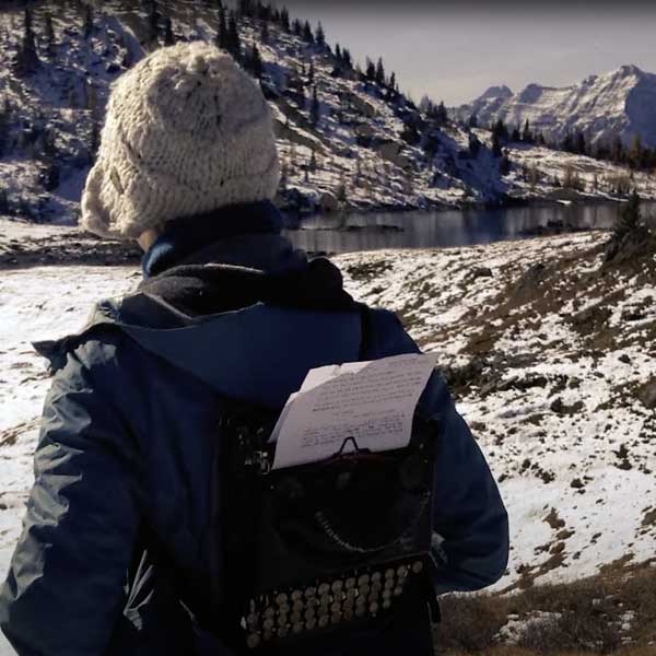 a person with a typewriter backpack in a snowy field