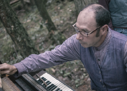 Actor Benjamin Goldenberg playing the piano in the forest. Photo by Sophia Dagher.