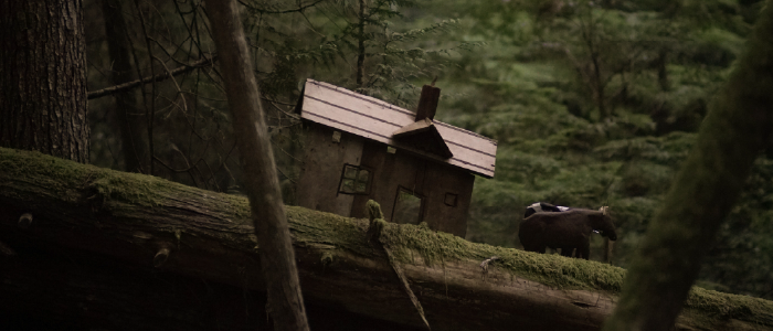 closeup of a model house and puppet oxen on a log
