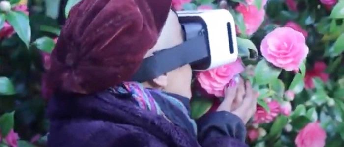A person wearing VR goggles smelling roses