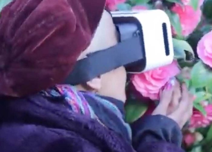 A person wearing VR goggles smelling roses
