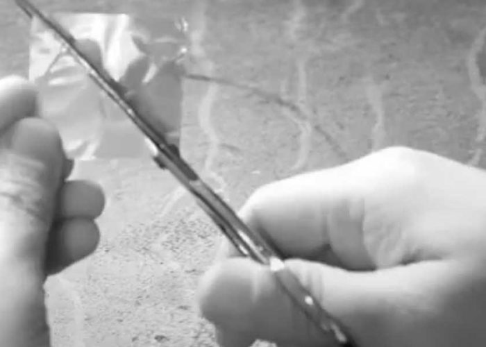 a closeup of a pair of hands cutting small plastic with scissors